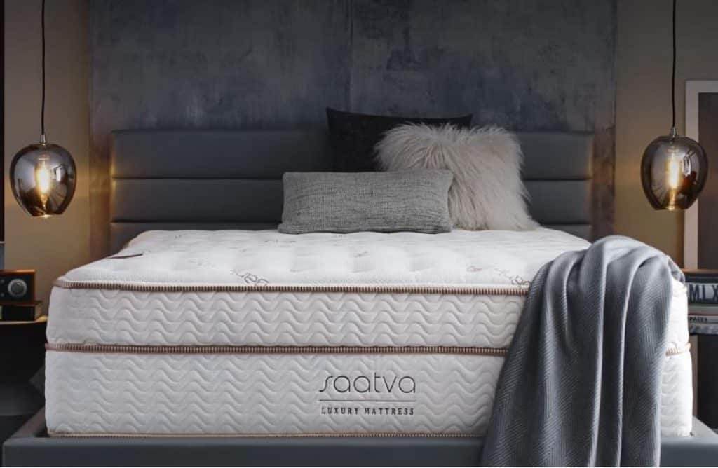 A bare Saatva luxury mattress against a gray backdrop.