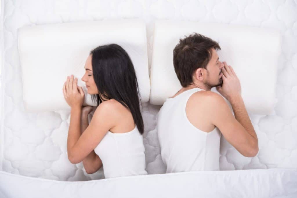 Couple sleeping in bed, facing away from each other.